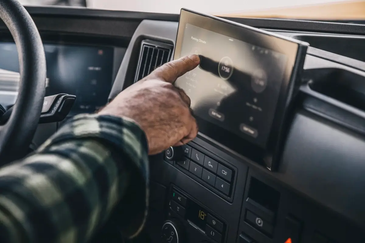 Męska dłoń obsługuje panel dotykowy w kabinie kierowcy pojazdu ciężarowego