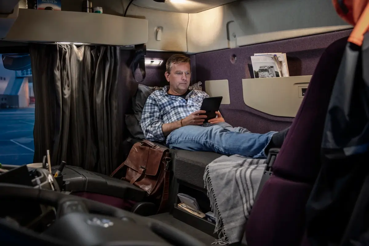 Męska dłoń obsługuje panel dotykowy w kabinie kierowcy pojazdu ciężarowego