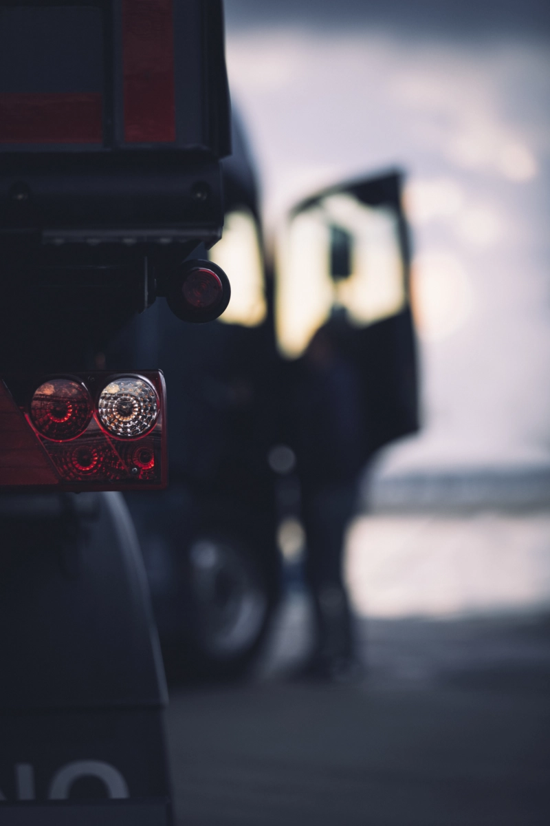 Samochód ciężarowy Volvo z 2 naczepami na których znajdują się kontenery. W tle widać magazyn kontenerów na wolnym powietrzu.