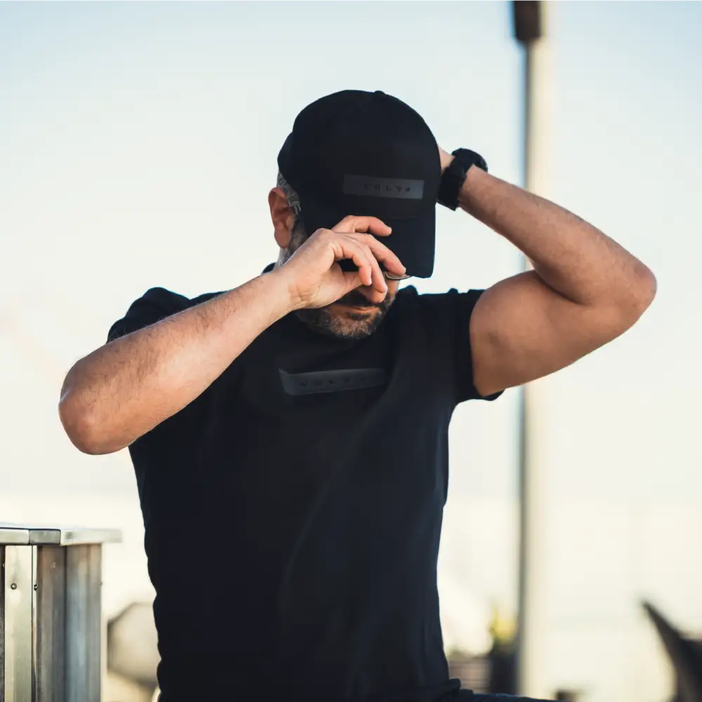 Mężczyzna ubierający czapkę z daszkiem w kolorze czarnym sygnowaną logiem Volvo