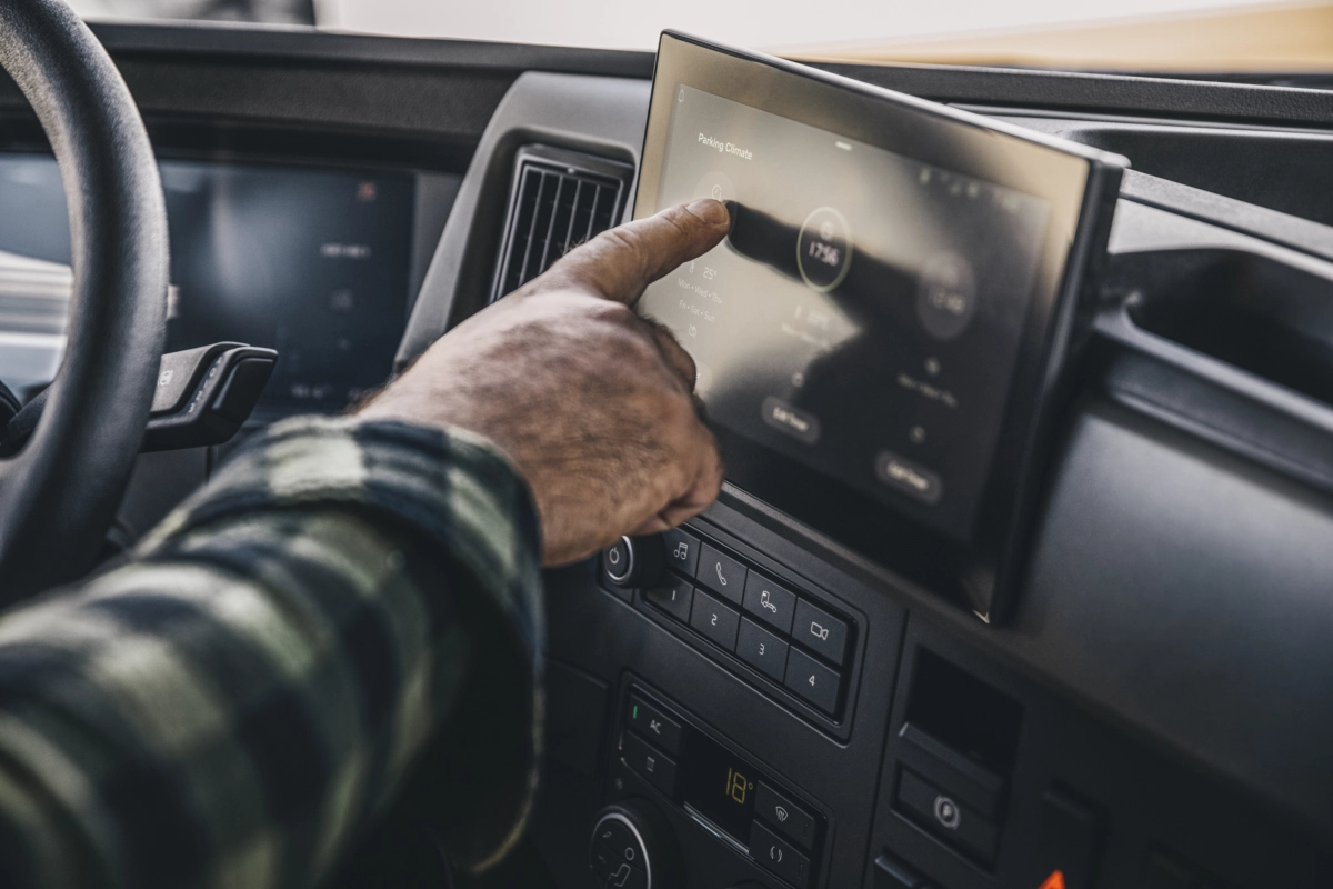 Męska dłoń obsługuje panel dotykowy w kabinie kierowcy pojazdu ciężarowego