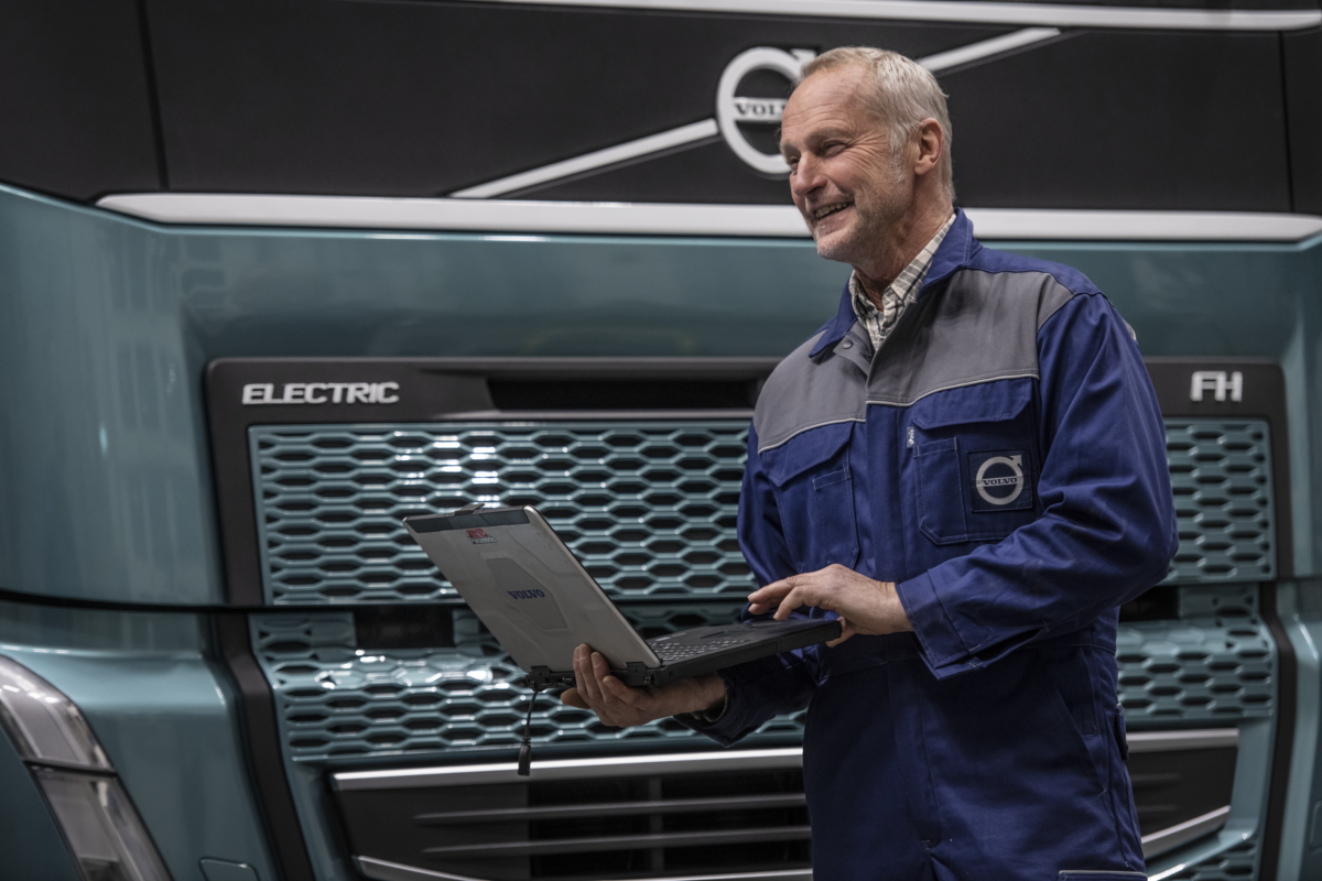 Mechanik z laptopem serwisowym stoi przed samochodem ciężarowym Volvo
